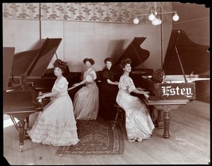 Vier vrouwen zittend aan piano